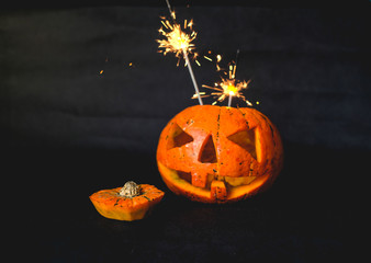 orange pumpkin on black background . cut out the eyes and mouth . the shining light is on.
