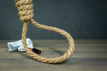 Rope noose around crumpled paper and pencil