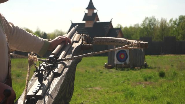Man preparing shooting with an ancient crossbow. Retro crossbow aiming in target. Ancient combat weapon.