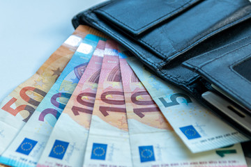 EURO-Geldscheine stecken in einem schwarzen Portemonnaie und stehen für Bargeld, Cash, Reichtum, passives Einkommen und Bezahlung im Finanzsektor