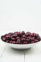 A lot of fresh sweet cherry fruit berries with water drops, close up on the plate on white background. Close up of pile of ripe cherries. Large collection of fresh red cherries. Ripe cherries texture 