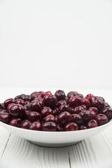 A lot of fresh sweet cherry fruit berries with water drops, close up on the plate on white background. Close up of pile of ripe cherries. Large collection of fresh red cherries. Ripe cherries texture 