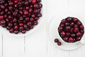A lot of fresh sweet cherry fruit berries with water drops, close up on the plate on white background. Close up of pile of ripe cherries. Large collection of fresh red cherries. Ripe cherries texture 
