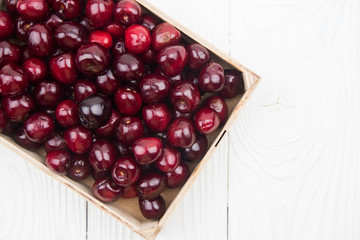 A lot of fresh sweet cherry fruit berries with water drops, close up in wooden box. Pile of ripe cherries. Large collection of fresh red cherries. Ripe cherries texture background.