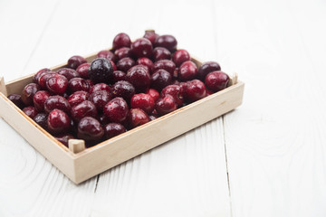 A lot of fresh sweet cherry fruit berries with water drops, close up in wooden box. Pile of ripe cherries. Large collection of fresh red cherries. Ripe cherries texture background.