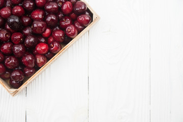 A lot of fresh sweet cherry fruit berries with water drops, close up in wooden box. Pile of ripe cherries. Large collection of fresh red cherries. Ripe cherries texture background.