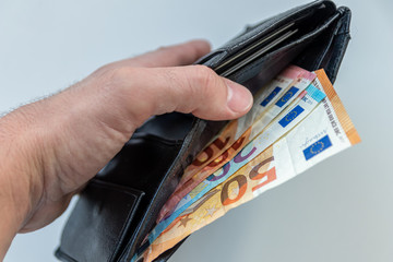 Männerhand hält ein geöffnetes Portemonnaie mit verschiedenen EURO-Geldscheinen als Ausdruck von...