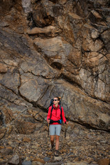 Woman in sportwear walking with hiking backpack and sticks
