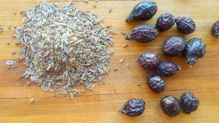 rose hips and caraway seeds on a wooden board
