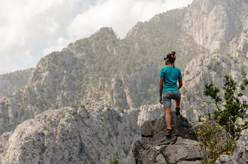 Rear view sporty woman standing on the rock on the beautiful landscape