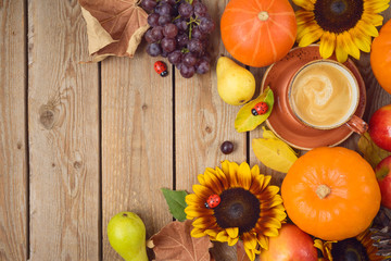 Autumn concept with coffee cup, pumpkin, apples and sunflowers on wooden table. Thanksgiving holiday background. Top view from above