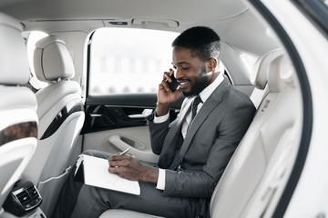 Afro businessman arranging his affairs in the car