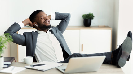 Young relaxed businessman enjoy listening music in office.