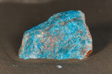 High grade rough natural Blue Apatite Specimen from Madagascar on wet sand  in front of the lake at sunrise.