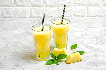 Melon lemonade, smoothie with ice and basil in a glass on the gray table. Summer refreshing and detox drink Rustic style Top view