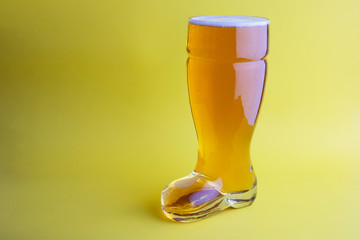 Beer in a boot beer glass in yellow background