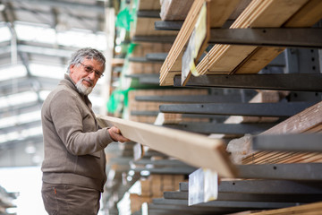 Man choosing and buying construction wood in a DIY store for his DIY home re-modeling project