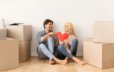 Fototapeta na wymiar Loving Couple Holding Red Paper Heart Sitting On Floor