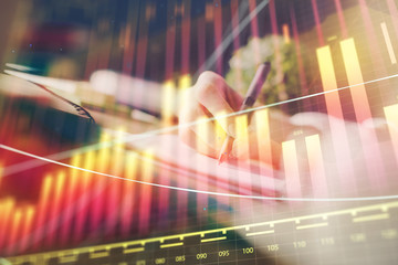 Financial forex graph displayed on hands taking notes background. Concept of research. Multi exposure