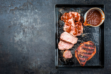 Barbecue dry aged sliced wagyu sirloin veal steak with hot chili sauce as top view on burnt metal tray with copy space left