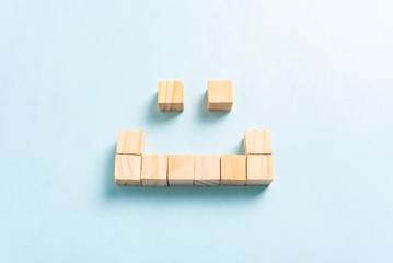 Happy face concept made with wooden block squares, on paper blue background. Customer service and content marketing concept.