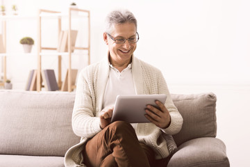 Senior man watching photos on tablet at home