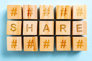 Share word on wooden toys square with hashtag and paper blue background. Social media news concept.