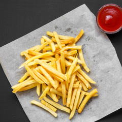 Fresh fried tasty french fries with sauce on a black background, overhead view. From above, top view.