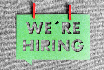"We're hiring" green banner on grey texture background. Job vacant and employment concept.