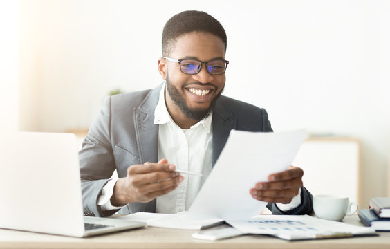 Handsome african american businessman working in office reading documents