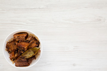 Homemade Filipino Adobo Pork in a white bowl, top view. Flat lay, from above, overhead. Copy space.