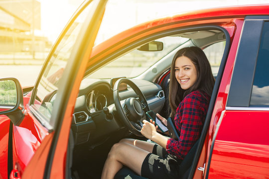 Attractive young woman in casual wear smiling while driving a car 