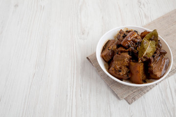 Homemade Filipino Adobo Pork with rice on a white wooden surface, side view. Copy space.