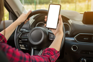 Beautiful woman sitting on the front driver seats in the car. Girl is using a smartphone. Hand closeup