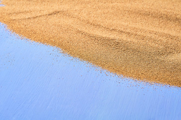 Scattered dry sea sand on blue scratched concrete. Space for text