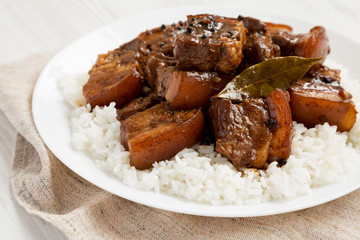 Homemade Filipino Adobo Pork with rice on a white plate, side view. Closeup.