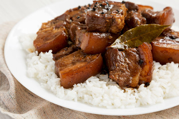 Homemade Filipino Adobo Pork with rice on a white plate, side view. Close-up.