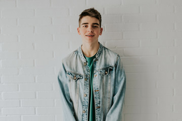 fashionable young boy or teenager on white brick wall