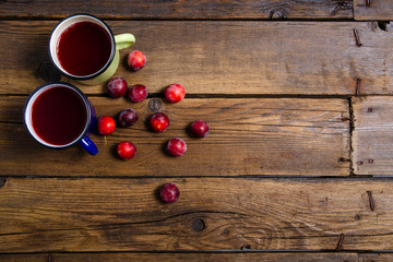 Cup compote plums on brown wooden background, top view empty space