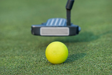 Putter back swinging for the golf ball.