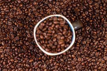 coffee beans background with a coffee mug full of coffee beans.