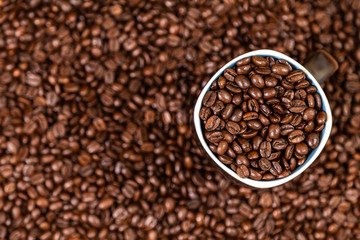 coffee beans background with a coffee mug full of coffee beans.