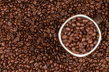 coffee beans background with a coffee mug full of coffee beans.