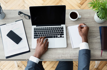 Black businessman working on his laptop sitting on workplace