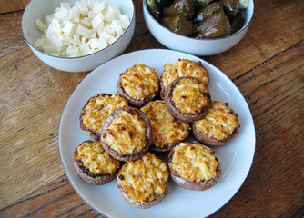 table with vegetarian food, filled mushrooms, cheese and wine leaves on plates
