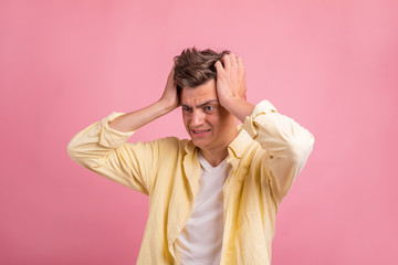 Portrait of young man with shocked facial expression  on pink background