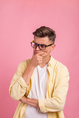 Young man thinking about things. Cropped shot of thoughtful young man standing near pink background