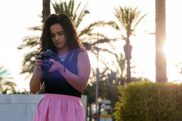 Portrait of young woman  making photos with a professional digital camera in a city.