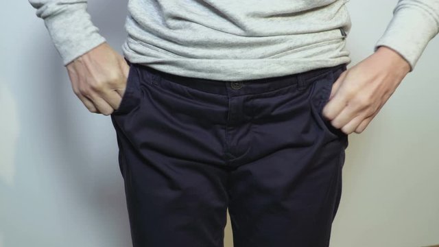 Woman showing empty pockets of trousers demonstrating she has no money