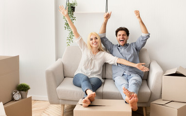 Cheerful Couple Relaxing On Sofa Celebrating Moving To New House